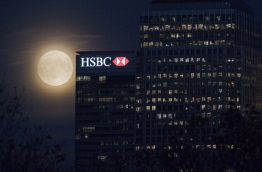 The moon rises behind HSBC bank in London's Docklands on November 13, 2016. HSBC announced October 9 that it aims to achieve net-zero carbon emissions across its investments by 2050. / AFP PHOTO / JUSTIN TALLIS