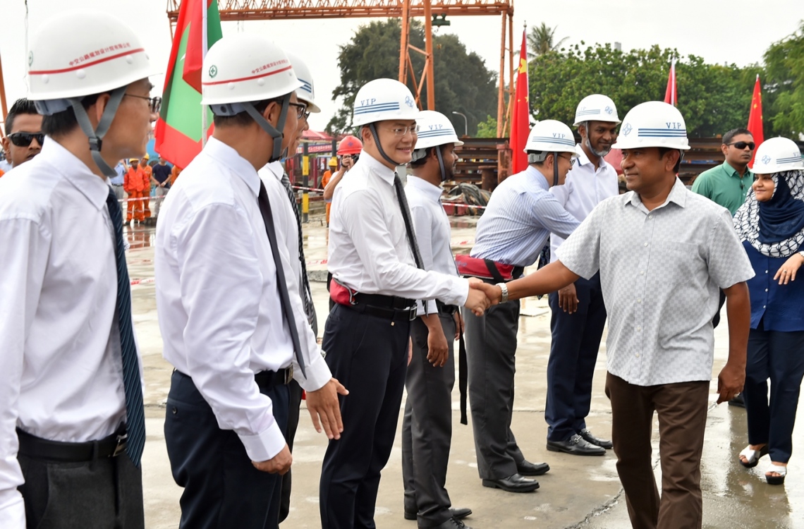 މާލެ: ޑިސެމްބަރު 28، 2016: ހުޅުލެ އާއި މާލެއާ ދެމެދު އަޅާ ބްރިޖުގެ މަސައްކަތް ކުރަމުން އަންނަ ސަރަހައްދަށް ރައީސް އަބްދުﷲ ޔާމީންގެ ދެކަނބަލުން ވަޑައިގަތުމުން، ޗައިނާގެ ސީސީސީސީ ކުންފުނީގެ އިސް ބޭފުޅުން އެކަނބަލުންނަށް މަރުހަބާ ކިޔުއްވަނީ.-- ފޮޓޯ: ރައީސް އޮފީސް