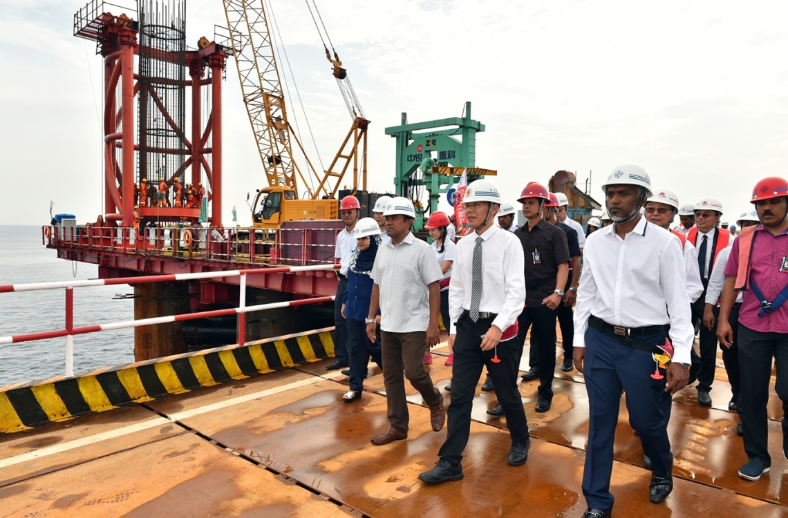 މާލެ: ޑިސެމްބަރު 28، 2016- މާލެ އާއި ހުޅުލެއާ ދެމެދު އަޅާ ބްރިޖުގެ މަސައްކަތް ކުރަމުން އަންނަ ސަރަހައްދަށް ރައީސް އަބްދުﷲ ޔާމީންގެ ދެކަނބަލުންނާއި ބައެއް ވަޒީރުންނާއި އަދި ޗައިނާގެ ސީސީސީސީ ކުންފުނީގެ އިސް ބޭފުޅުން ވަޑައިގެން ބައްލަވައި ލައްވަނީ.-- ފޮޓޯ: ރައީސް އޮފީސް