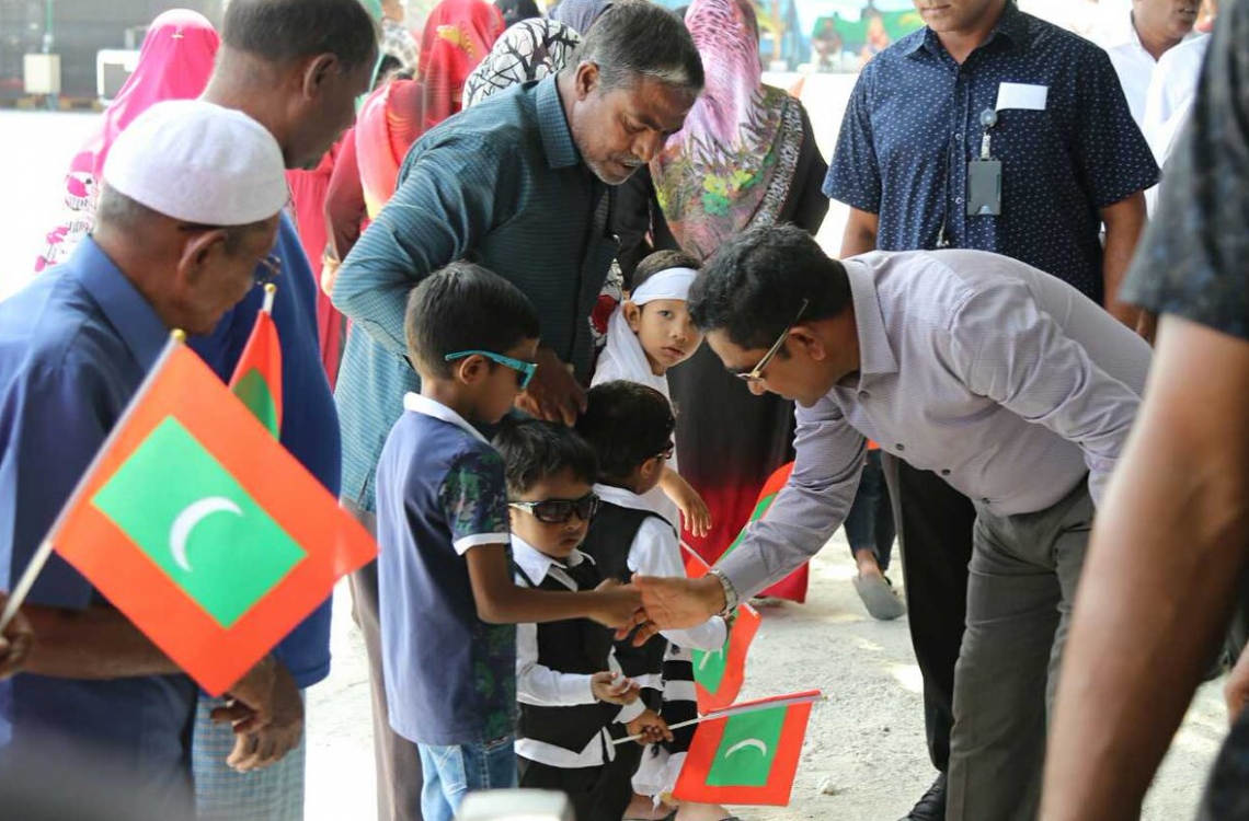 މިދިޔަ ހަފުތާގައި ރައީސް ޔާމީން ތުލުސްދު އަށް ވަޑައިގެން އެ ރަށުގެ ކުޑަކުއްޖަކާ ސަލާމްކުރައްވަނީ: އަންނަ އަހަރުގެ އިންތިޚާބަށް ކެމްޕޭންގެ ހަރަކާތްތައް މިހާރު ވެސް ވަނީ ފައްޓަވާފައި. --ފޮޓޯ: ހައުސިން މިނިސްޓްރީ