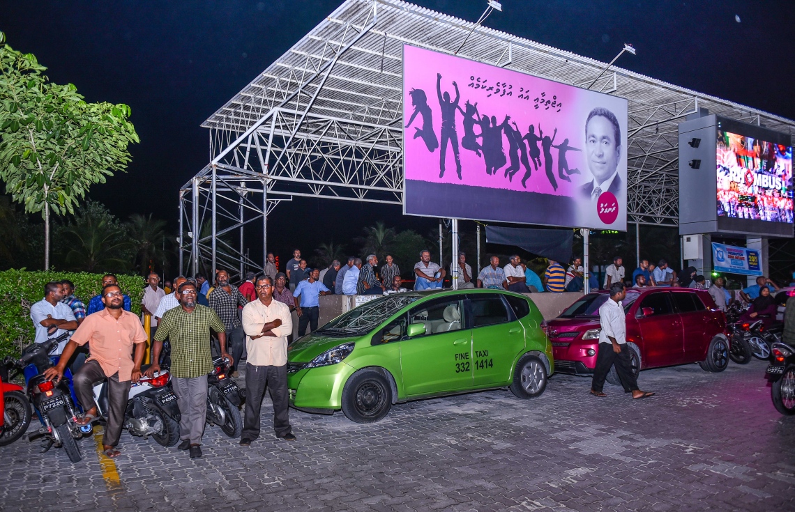 މާލެ، މޭ 16، 2017- އިދިކޮޅު ކޯލިޝަނުން އެމްޑީޕީގެ ހަރުގޭގައި ބޭއްވި ޖަލްސާ އަޑުއެހުމަށް، ހަރުގެ ކުރިމައްޗަށްވާ ގޮތަށް ހަރުކޮށްފައިވާ، ރައީސް އަބްދުﷲ ޔާމީނުގެ ފޮޓޯފުޅު ޖަހާފައިވާ ބިލްބޯޑެއްގެ ކައިރީގައި ބަޔަކު މަޑުކޮއްލައިގެން.---މިހާރު ފޮޓޯ: ހުސެއިން ވަހީދު