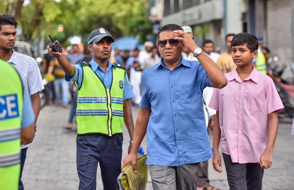 މާލެ: ޖޫން 25، 2017- މާފަންނު ސްޓޭޑިއަމްގައި ބޮޑު ޖަމާއަތުގައި މި އަހަރުގެ ފިތުރު އީދު ނަމާދަށް ކުޑަކުއްޖަކު ގޮވައިގެން ދިޔަ މީހަކަށް ފުލުހަކު މަގު ދައްކަނީ.---މިހާރު ފޮޓޯ: ނިޝާން އަލީ