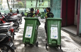 WAMCO staff carrying waste bins across Male' City.