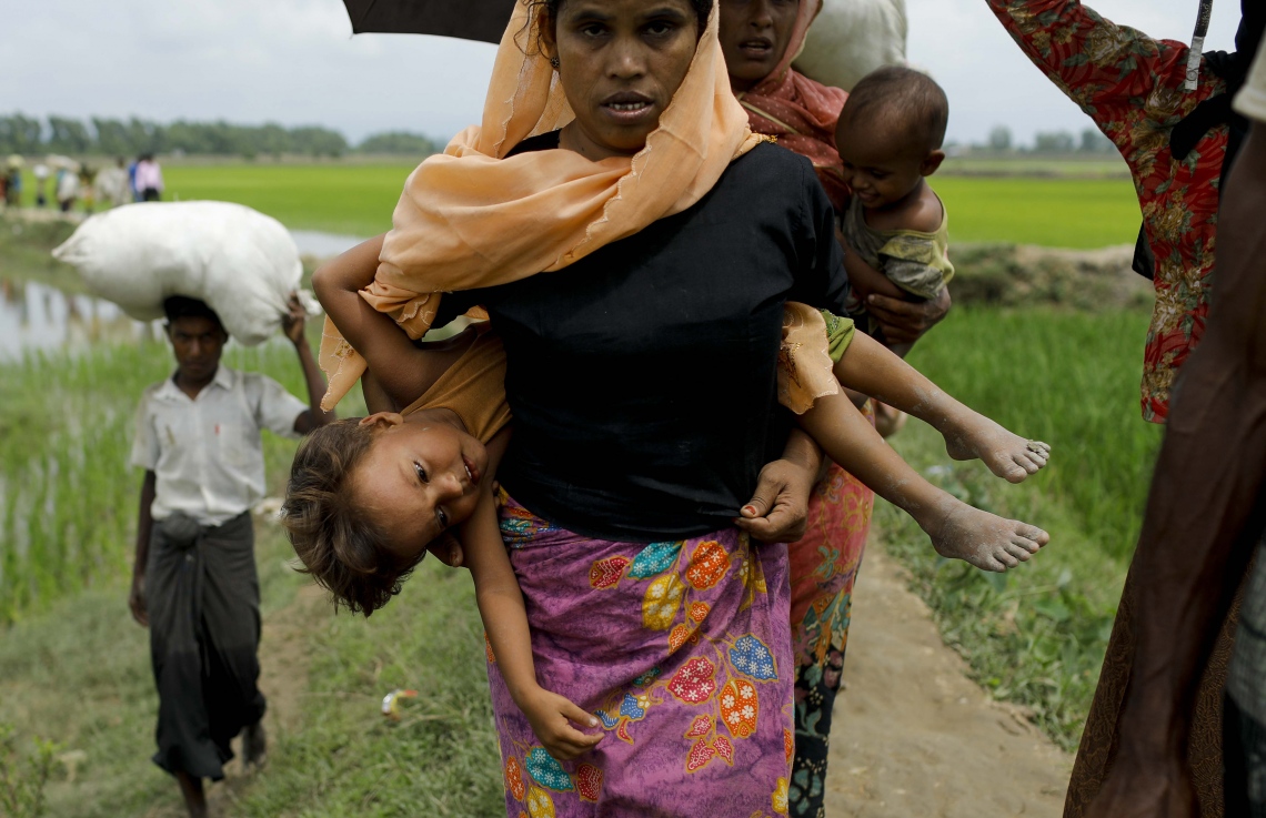 މިއަންމާގެ ރެފިއުޖީ މުސްލިމް އަންހެނަކު ކުޑަ ކުދިންތަކެއް ގޮވައިގެން ދަނީ. --ފޮޓޯ:އޭއެފްޕީ