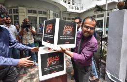 Raajje TV CEO Fiyaz walking into the Broadcasting Commission office with a fund box. PHOTO: HUSSAIN WAHEED / MIHAARU