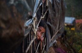 A Rohingya girl looks out from a makeshift shelters at Hakimpara refugee camp in the Bangladeshi district of Ukhia on November 13, 2017.  
More than 600,000 Rohingya have arrived in Bangladesh since a military crackdown in Myanmar in August triggered an exodus, straining resources in the impoverished country. / AFP PHOTO / Munir UZ ZAMAN