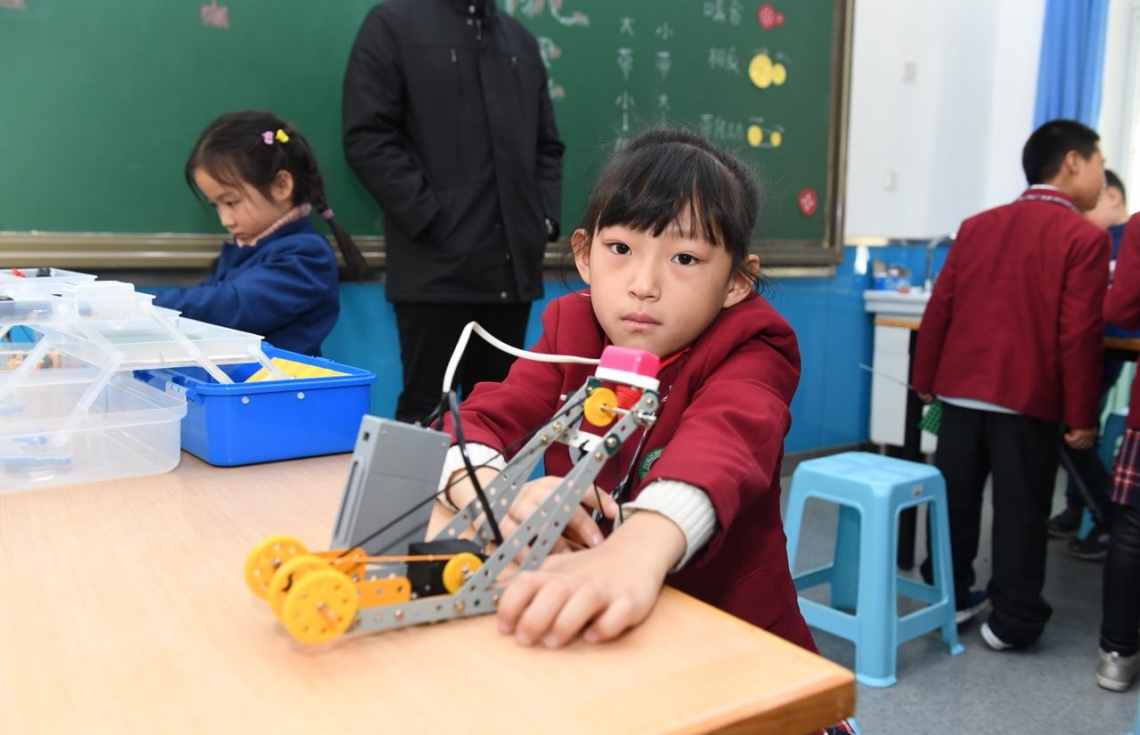 ޗައިނާ، ބެއިޖިން: ޑިސެމްބަރު 7، 2017- ރައީސް އަބްދުﷲ ޔާމީންގެ އަނބިކަނބަލުން ފަސްޓް ލޭޑީ ފާތިމަތު އިބްރާހީމް، ޗައިނާގެ ސްކޫލެއް ކަމަށްވާ ބެއިޖިން ޒިޝުކޫ އެލިމެންޓަރީ ސްކޫލަށް މިއަދު ޒިޔާރަތް ކުރެއްވި ވަގުތު، އެ ސްކޫލްގެ ކުއްޖަކު ކެމެރާ އަށް ބަލަހައްޓައިގެން.---ފޮޓޯ: ރައީސް އޮފީސް