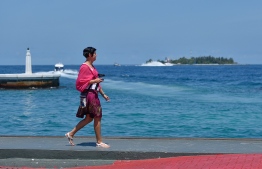 Tourist walking along the jetty in capital Mal'e City.