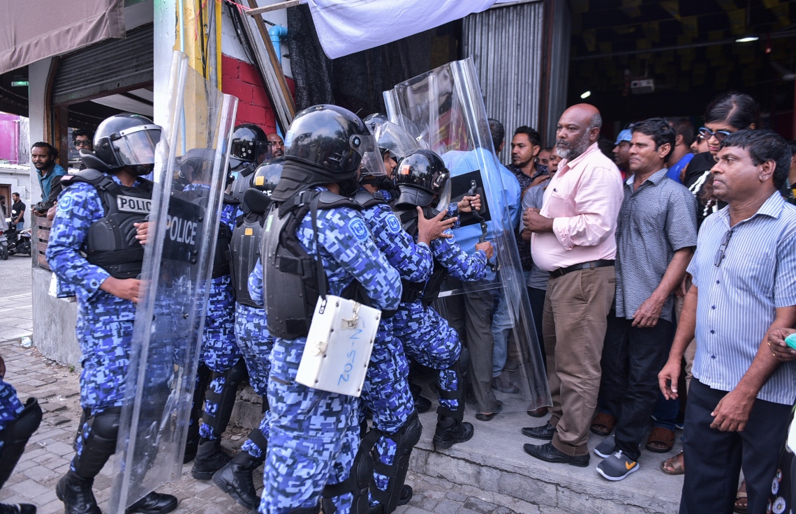 މާލެ: ފެބްރުއަރީ 16، 2018- ސަރުކާރާ ދެކޮޅަށް އިދިކޮޅު ހަރަކާތުން ފަހުގެ ތާރީޚެއްގައި ބާއްވާ ބޮޑު މުޒާހަރާ އަށް ތައްޔާރުވުމަށް "ވޯމްއަޕް މުޒާހަރާ" ގެ ނަމުގައި ކުރިއަށް ގެންދަން އުޅުނު އެއްވުން ރޫޅާލުމަށް އެސްއޯ ފުލުހުން އެމްޑީޕީގެ ހަރުގެ ތެރެއަށް ޝީލްޑާއެކު ވަންނަނީ: މި ހަރުގެ ވެސް ފުލުހުންގެ ބެލުމުގެ ދަށަށް ގެނައި.---ފޮޓޯ: ހުސެއިން ވަހީދު/މިހާރު