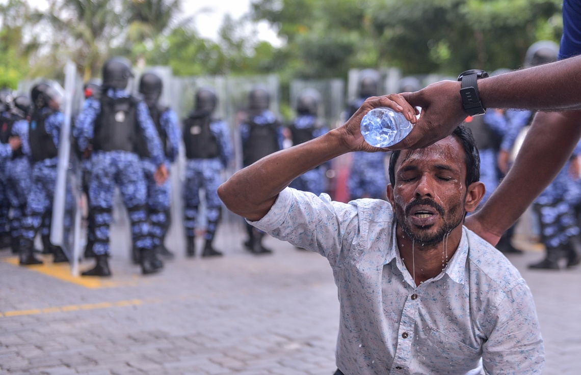 މާލެ: ފެބްރުއަރީ 16، 2018- ސަރުކާރާ ދެކޮޅަށް އިދިކޮޅު ހަރަކާތުން ފަހުގެ ތާރީޚެއްގައި ބާއްވާ ބޮޑު މުޒާހަރާ އަށް ތައްޔާރުވުމަށް "ވޯމްއަޕް މުޒާހަރާ" ގެ ނަމުގައި ކުރިއަށް ގެންދަން އުޅުނު އެއްވުން ރޫޅާލުމަށް އެސްއޯ ފުލުހުން ޕެޕާ ސްޕްރޭ ޖެހުމުން އޭގެ އަސަރުކުރި، އިހަވަންދޫ ދާއިރާގެ މެމްބަރު މުހައްމަދު އަބްދުﷲ (މުހަންމާ) ގެ ބޮލަށް ފެން އަޅަނީ.---ފޮޓޯ: ހުސެއިން ވަހީދު/މިހާރު