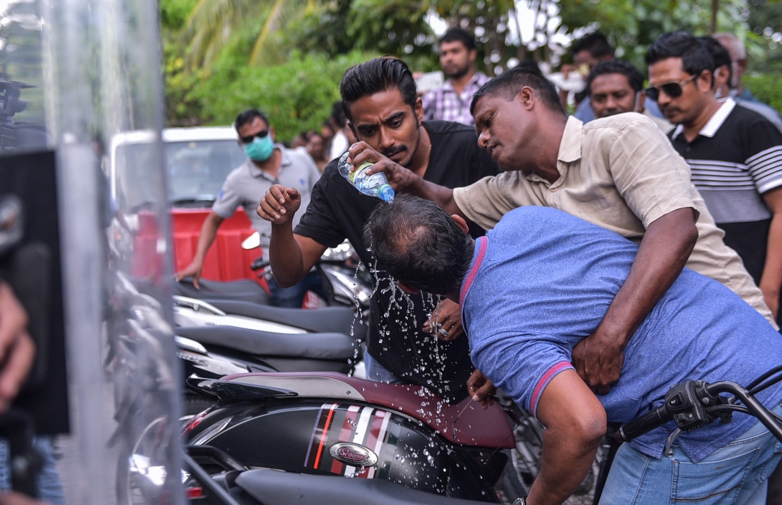 މާލެ: ފެބްރުއަރީ 16، 2018- ސަރުކާރާ ދެކޮޅަށް އިދިކޮޅު ހަރަކާތުން ފަހުގެ ތާރީޚެއްގައި ބާއްވާ ބޮޑު މުޒާހަރާ އަށް ތައްޔާރުވުމަށް "ވޯމްއަޕް މުޒާހަރާ" ގެ ނަމުގައި ކުރިއަށް ގެންދަން އުޅުނު އެއްވުން ރޫޅާލުމަށް ފުލުހުން ޖެހި ޕެކާ ސްޕްރޭގެ އަސަރުކުރި މީހަކަށް ބަޔަކު އެހީތެރިވަނީ.---ފޮޓޯ: ހުސެއިން ވަހީދު/މިހާރު