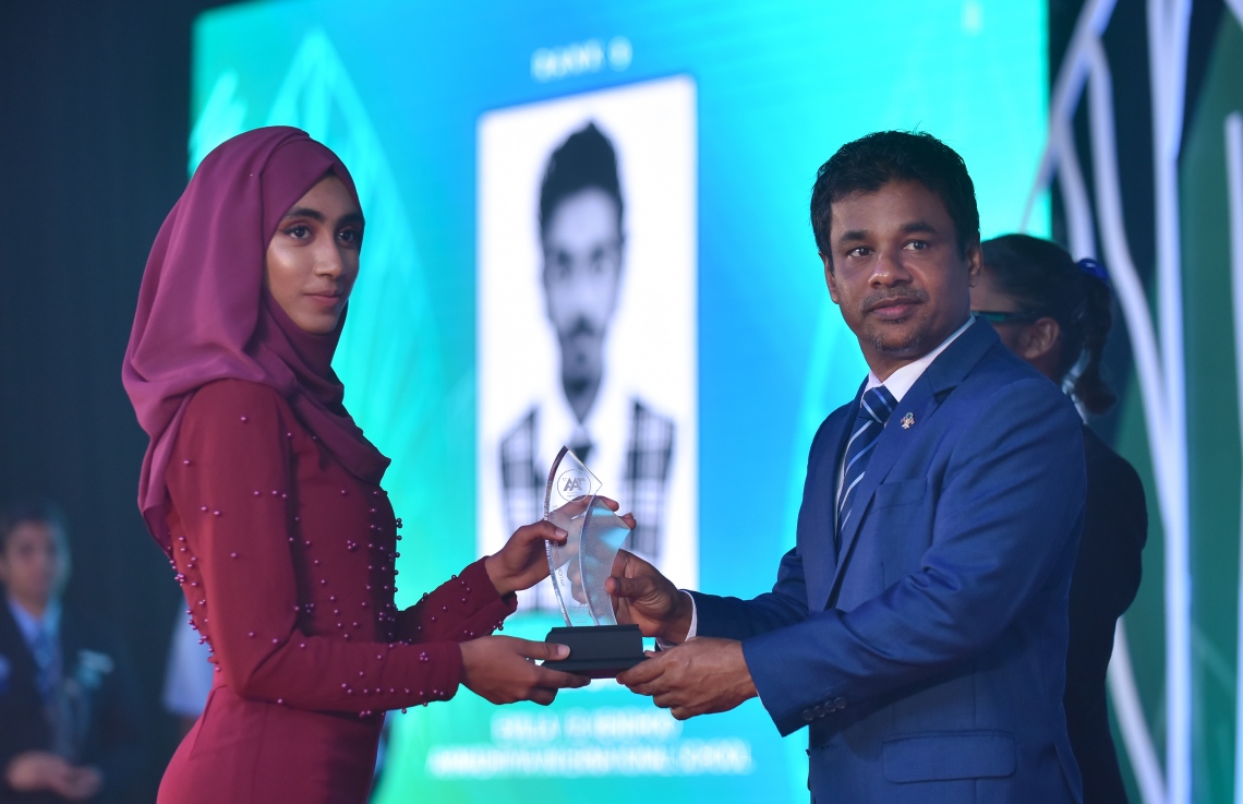 މާލެ: މާޗް 4، 2018- މިދިޔަ އަހަރުގެ އޭ ލެވެލް އިމްތިހާނުގެ ޓޮޕް އެޗީވާސް އެވޯޑް ދިނުމުގެ ރަސްމިއްޔާތުގައި، ހެލްތު މިނިސްޓަރު އަބްދުﷲ ނާޒިމް ދަރިވަރަކަށް އިނާމު ދެއްވަނީ---ފޮޓޯ: ހުސައިން ވަހީދު/މިހާރު