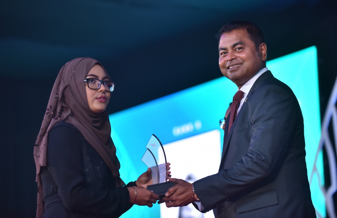 މާލެ: މާޗް 4، 2018- މިދިޔަ އަހަރުގެ އޭ ލެވެލް އިމްތިހާނުގެ ޓޮޕް އެޗީވާސް އެވޯޑް ދިނުމުގެ ރަސްމިއްޔާތުގައި، އެންވަޔަރުމެންޓް މިނިސްޓަރު ތޯރިގް އިބްރާހީމް ދަރިވަރަކަށް އިނާމު ދެއްވަނީ---ފޮޓޯ: ހުސައިން ވަހީދު/މިހާރު