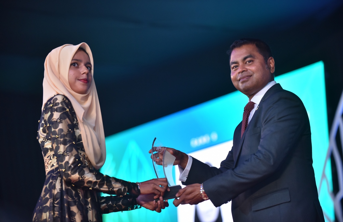 މާލެ: މާޗް 4، 2018- މިދިޔަ އަހަރުގެ އޭ ލެވެލް އިމްތިހާނުގެ ޓޮޕް އެޗީވާސް އެވޯޑް ދިނުމުގެ ރަސްމިއްޔާތުގައި، އެންވަޔަރުމެންޓް މިނިސްޓަރު ތޯރިގް އިބްރާހީމް ދަރިވަރަކަށް އިނާމު ދެއްވަނީ---ފޮޓޯ: ހުސައިން ވަހީދު/މިހާރު