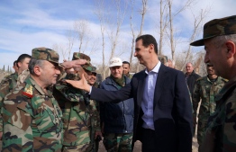 A handout picture released by the official Facebook page of the Syrian Presidency on March 18, 2018, shows Syrian President Bashar al-Assad (C) shaking hands with government troops in Eastern Ghouta, in the leader's first trip to the former rebel enclave outside Damascus in years.
Rebels have held out in Eastern Ghouta since 2012, but a regime assault in the last month has retaken more than 80 percent of the former opposition bastion, the Britain-based Syrian Observatory for Human Rights war monitor says. / AFP PHOTO / Syrian Presidency Facebook page / HO / 
