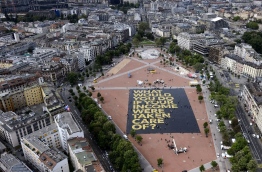 A giant poster reading: "What would you do if your income was taken care of?" is laid out on May 14, 2016 in Plainpalais place in Geneva (AFP Photo/Fabrice Coffrini)