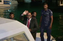 Former VP Adheeb waves as he is escorted to prison after being sentenced to 10 years for weapon possession. MIHAARU PHOTO/MOHAMED SHARUHAAN