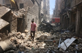 A man walks on the rubble of a destroyed building following reported air strikes by Syrian government forces in the rebel-held Shaar neighbourhood of the northern city Aleppo on June 8, 2016. Syrian government air strikes on rebel-held neighbourhoods of the divided second city Aleppo killed at least 15 civilians, the Syrian Observatory for Human Rights said. The monitoring group said at least 10 of the dead came in strikes just outside the Al-Bayan clinic in the Shaar neighbourhood. / AFP PHOTO 