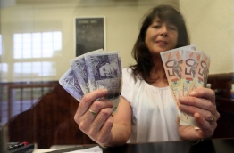 Delia Breen, who works in a money exchange office at the border between Newry in Northern ireland and Dundalk in The Republic of Ireland poses with handfuls of Sterling notes and Euro notes, on June 7, 2016. AFP PHOTO