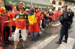 Police officers stand guard by Belgium supporters wearing Belgian football jersey and Belgium's national flag as they gather in the streets of Bordeaux, on June 18, 2016 ahead of the Euro 2016 group E football match between Belgium and Ireland at the Matmut Atlantique stadium in Bordeaux. / AFP PHOTO / IROZ GAIZKA