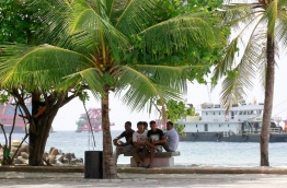 Some expats take shelter under a palm tree on a hot day in the capital Male. Government is looking to impose a tax on remittances to raise revenue. MIHAARU PHOTO/MOHAMED SHARUHAAN