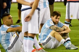 Argentina's Lionel Messi (R) and Gabriel Mercado sit on the ground in dejection after being defeated by Chile in the penalty shoot-out of the Copa America Centenario final in East Rutherford, New Jersey, United States, on June 26, 2016. / AFP PHOTO / ALFREDO ESTRELLA