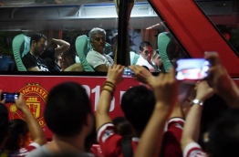 Manchester United coach Jose Mourinho (top C) looks at fans from the team bus after a training session a day before the 2016 International Champions Cup football match between Manchester City and Manchester United, in Beijing on July 24, 2016. / AFP PHOTO / GREG BAKER