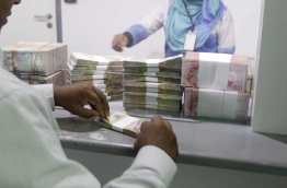 A man counts a stack of notes at a MMA counter. MIHAARU FILE PHOTO/MOHAMED SHARUHAAN