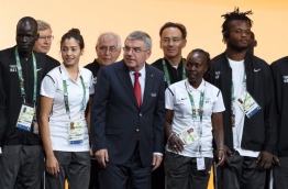 International Olympic Committee (IOC) President Thomas Bach (C) poses with a team of Refugee Olympic Athletes and their trainers during the 129th IOC session in Rio de Janeiro on August 2, 2016, ahead of the Rio 2016 Olympic Games. / AFP PHOTO / FABRICE COFFRINI