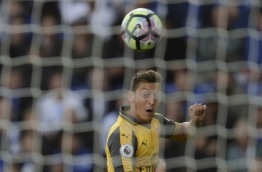 Arsenal's German midfielder Mesut Ozil (top) tries to cross the ball over Leicester City's Danish goalkeeper Kasper Schmeichel (bottom) during the English Premier League football match between Leicester City and Arsenal at King Power Stadium in Leicester, central England on August 20, 2016. / AFP PHOTO / OLI SCARFF / 