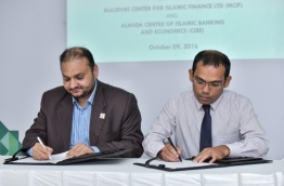 Maldives Centre for Islamic Finance's managing director Ibrahim Didi (R) and AlHuda Centre of Islamic Banking &amp; Economics' CEO Muhammad Zubair Mughal sign agreement for CIBE to enhance MCIF's services and train its staff. PHOTO: NISHAN ALI/MIHAARU