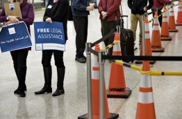 Volunteers wait to offer free legal advice to travelers at the international arrivals hall at Washington Dulles International Airport February 6, 2017 in Dulles, Virginia. / AFP PHOTO / Brendan Smialowski