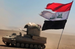 An Iraqi flag flutters above an armoured vehicle as troops, supported by the Hashed al-Shaabi (Popular Mobilisation) paramilitaries, advance near the village of Sheikh Younis, south of Mosul, after the offencive to retake the western side of the city from Islamic State (IS) group fighters commenced on February 19, 2017. / AFP PHOTO / Ahmad al-Rubaye