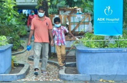 A man and child donning face masks for protection against viral fever leave ADK Hospital. PHOTO: HUSSAIN WAHEED/MIHAARU