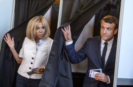 French President Emmanuel Macron (R) and his wife Brigitte Macron (L) leave the voting booth at a polling station to vote during the first round of the French legislative election in Le Touquet, on June 11, 2017. / AFP PHOTO / POOL / Christophe Petit Tesson