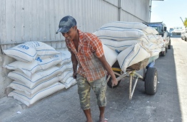 A man pulls a cart loaded with sacks of various staple food to STO's godown.