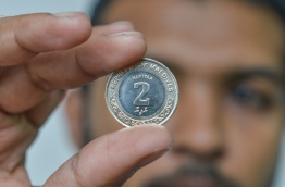 A man holds up the new, lighter MVR 2 coin. PHOTO: HUSSAIN WAHEED/MIHAARU