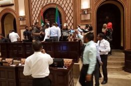 Security forces remove opposition lawmakers gathered at the parliament speaker's table while lawmaker protest.