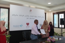 Fenaka’s MD Ahmed Shareef and HRCM's President Aminath Eenas show the resolution to protect and ensure human rights.