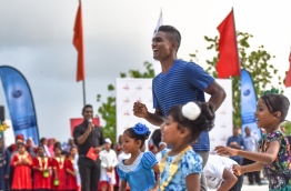 Hassan Saaid enjoys a friendly race with children at the Sports Stars Fiesta in Maafushi. PHOTO: HUSSAIN WAHEED/MIHAARU
