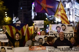 Demonstrators hold posters demanding "Freedom for political prisoners" with pictures of detained leaders of Catalan separatist groups Jordi Cuixart and Jordi Sanchez during a demonstration called by Coordinadora 25S in favour of the Catalan Republic and under the motto "Goodbye mafia, hello Republic" in Madrid on November 5, 2017. / AFP PHOTO / Rafa RIVAS
