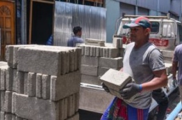An expatriate worker carries cement bricks to a construction site. PHOTO/MIHAARU