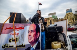 A supporter of Egyptian President Abdel Fattah al-Sisi stands in the back of a pickup truck bearing his portrait and loudspeakers, in the capital Cairo's Tahrir square on January 25, 2018, as the country marks the seventh anniversary of the 2011 uprising that ended the 30-year reign of former President Hosni Mubarak. / AFP PHOTO / MOHAMED EL-SHAHED