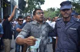 Police taking Mahloof aside from a rally. PHOTO/ALI NISHAN/MIHAARU