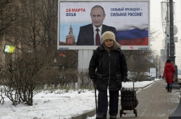 (FILES) In this file photo taken on January 12, 2018 people pass by a billboard with an image of Russia's President Vladimir Putin and lettering "Strong president - Strong Russia!" in Saint Petersburg. / AFP PHOTO / Olga MALTSEVA