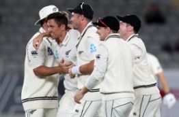 New Zealand's Trent Boult (L) celebrates with Tim Southee (C) and teammates after taking the wicket of England's Joe Root on the fourth day of the day-night Test cricket match between New Zealand and England at Eden Park in Auckland on March 25, 2018. / AFP PHOTO / Michael BRADLEY