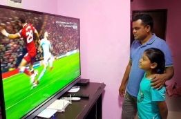 A man and a child watch Dhiraagu TV after its launching in GA. Villingili. PHOTO/MIHAARU