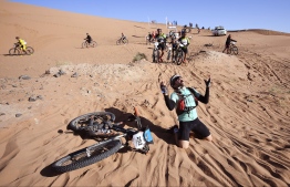 A competitor reacts after crossing a sand dune during Stage 4 of the 13th edition of the Titan Desert 2018 mountain biking race between Boumalne Dades and Merzouga in Morocco on May 2, 2018. 
The Titan Desert 2018 is 600 kilometre mountain bike race completed over six days, snaking between Boumalne Dades, at the foot-slopes of the High Atlas summits, and Erfoud, an oasis town in the Sahara Desert. / AFP PHOTO / FRANCK FIFE