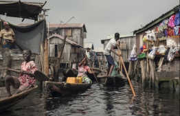 People navigate the the waterways of Makoko waterfront community in Lagos on May 15, 2018. 
Members of various waterfront communities and the Nigerian Slum/Informal Settlement Federation have protested on the day marking one year anniversary of the forced eviction of the Otodo Gbame community, a Lagos shanty town, from their waterfront location. / AFP PHOTO / STEFAN HEUNIS