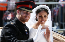 Britain's Prince Harry, Duke of Sussex and his wife Meghan, Duchess of Sussex wave from the Ascot Landau Carriage during their carriage procession on the Long Walk as they head back towards Windsor Castle in Windsor, on May 19, 2018 after their wedding ceremony.  / AFP PHOTO / POOL / Aaron Chown